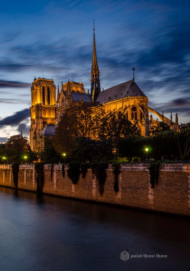 Notre Dame Cathedral at Sunset with lights on and Seine in foreground