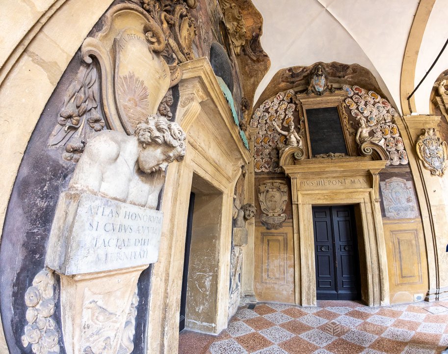 Ornate vaulted ceilings and stone sculptures inside the Archiginnasio of Bologna, the original seat of the University of Bologna.