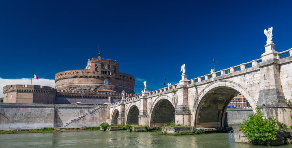 Castel Sant'Angelo and the bridge of angels (Ponte Sant'Angelo) reflecting in the Tiber River at sunset in Rome.