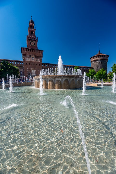 Castello Sforzesco entrance and Filarete Tower with the central fountain in Milan, Italy.