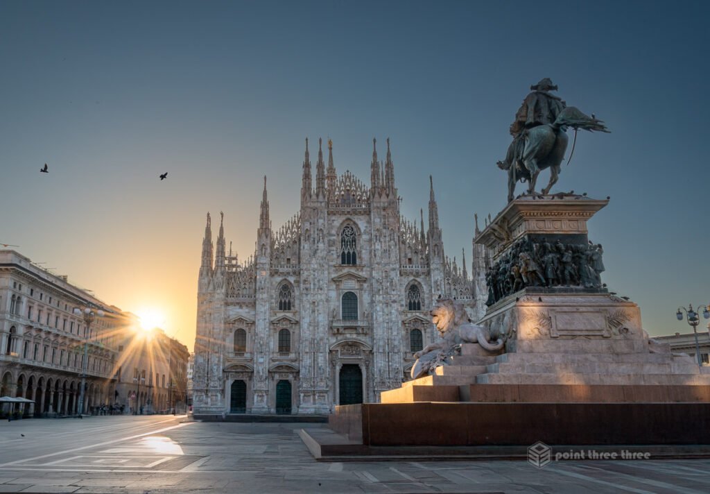 Duomo di Milano (Milan Duomo) cathedral at sunrise with sun starburst and equestrian statue in Piazza del Duomo