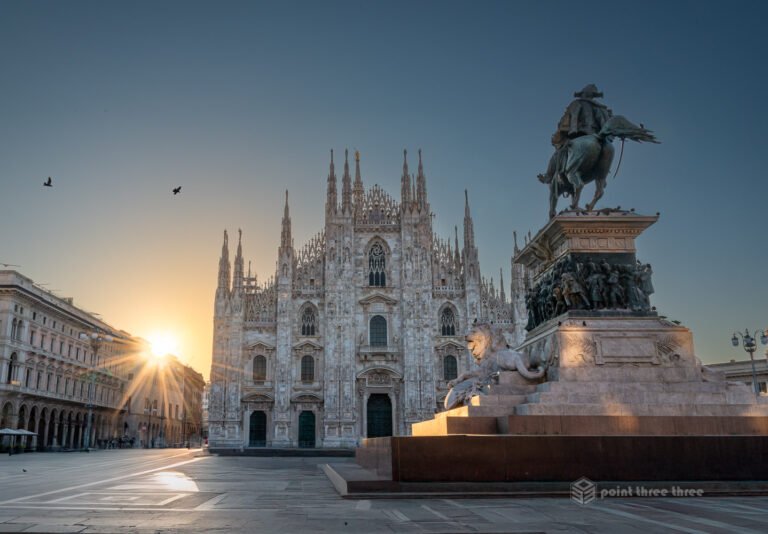 Duomo di Milano (Milan Duomo) cathedral at sunrise with sun starburst and equestrian statue in Piazza del Duomo