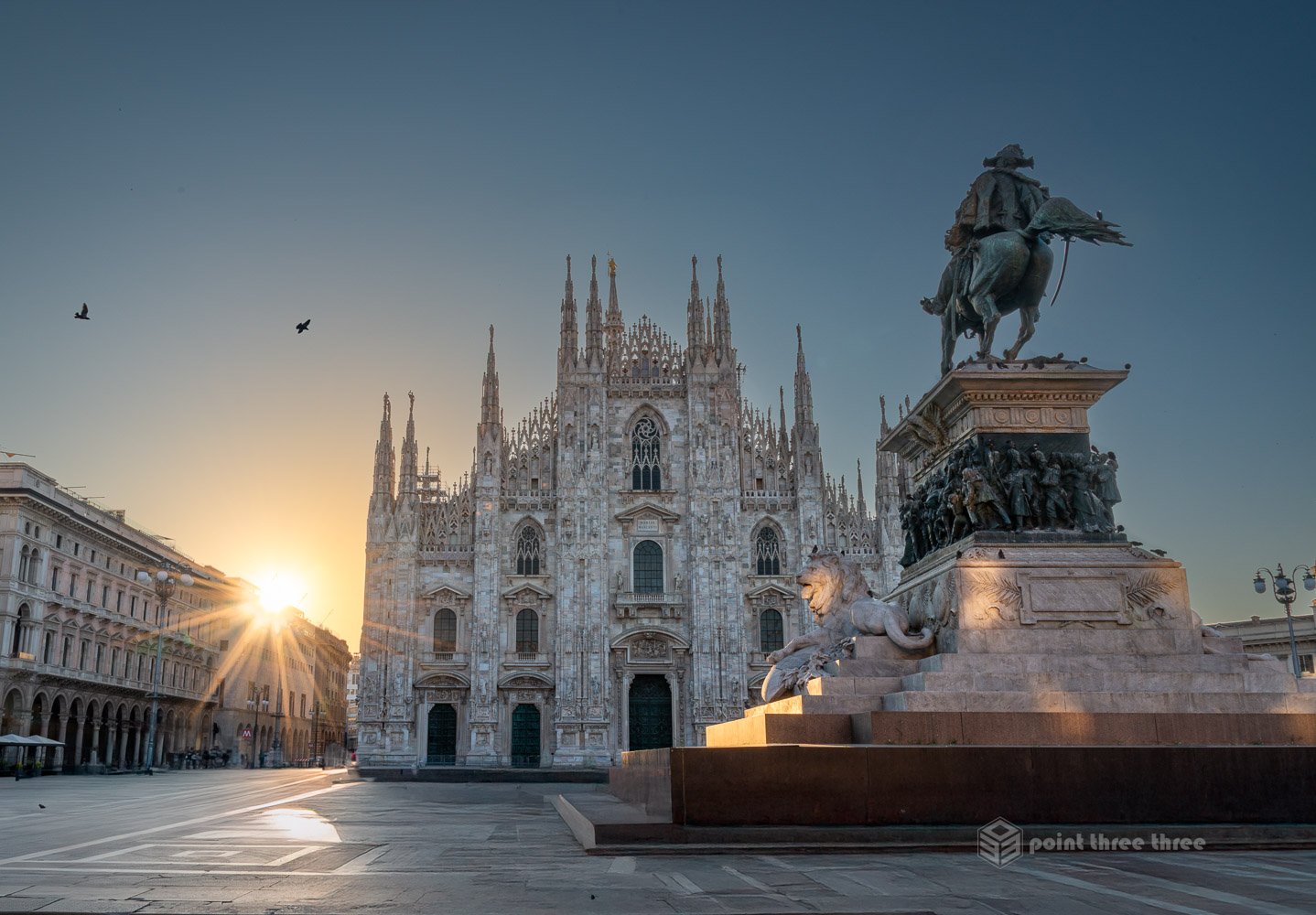 Duomo di Milano (Milan Duomo) cathedral at sunrise with sun starburst and equestrian statue in Piazza del Duomo