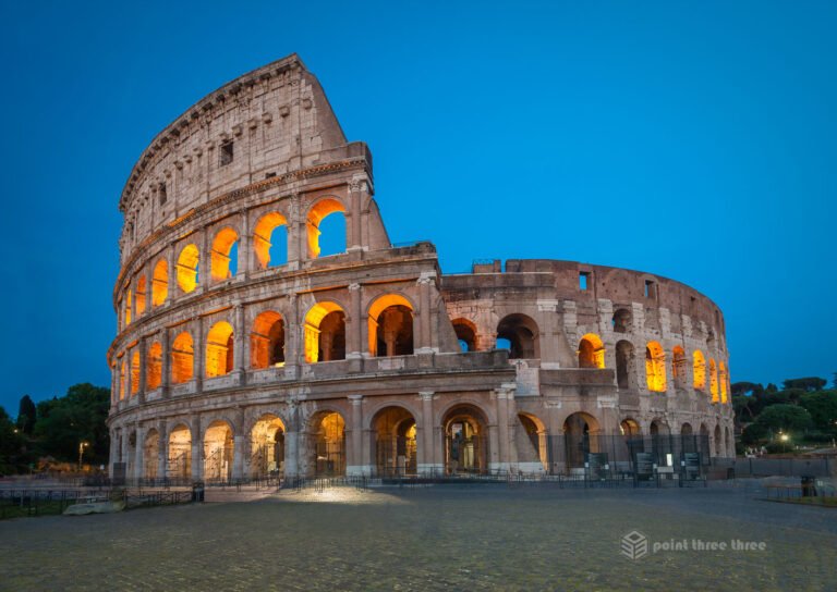 Roman Colosseum illuminated with golden lights at blue hour twilight with deep blue sky Rome Italy