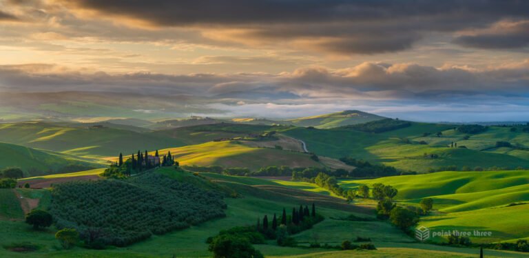 Sunrise over Podere Belvedere in Tuscany, with rolling green hills, morning mist, and cypress trees in Val d’Orcia, Italy