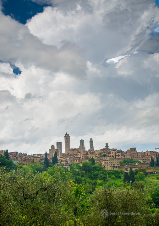 Panoramic view of the medieval towers of San Gimignano skyline rising above the Tuscan countryside and vineyards.