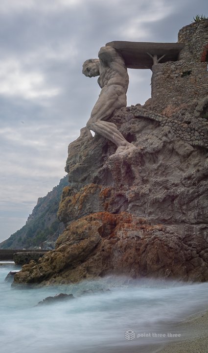 he Giant statue of Neptune carved into the rock cliffs at Fegina Beach in Monterosso al Mare, Cinque Terre.